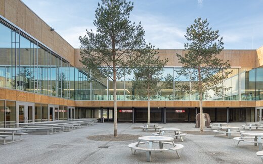 Moderner Innenhof mit Sitzbänken und Glasfassade Innenhof mit Sitzgelegenheiten und Bäumen